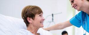 A woman in a hospital bed smiling at a nurse