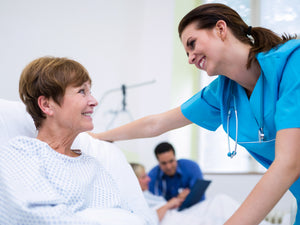 A woman in a hospital bed smiling at a nurse