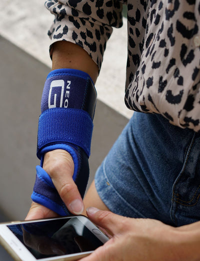 Woman wearing Neo G Stabilized Wrist Brace, holding a phone