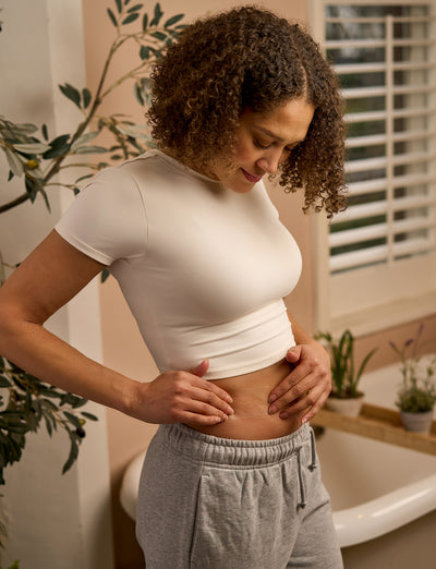 A woman applying the Opti-Heal Ultra Thin Hydrocolloid dressing to her stomach